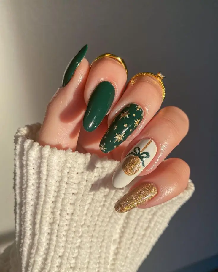 Emerald green almond nails with gold starburst confetti, a gold glitter nail, and a white ornament accent